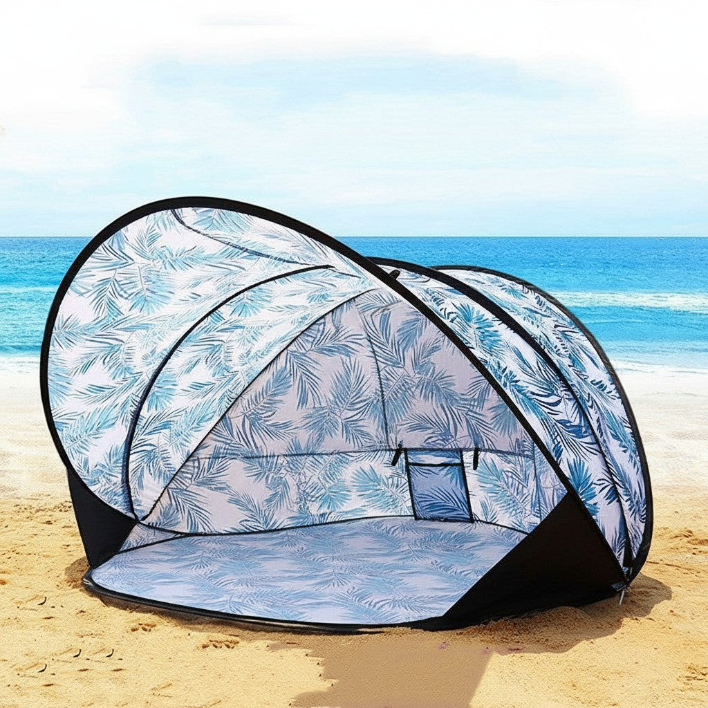 ZenZon Nordic pop-up beach tent with blue leaf print, UV protection, and waterproof material. A woman sits inside on a sandy beach.