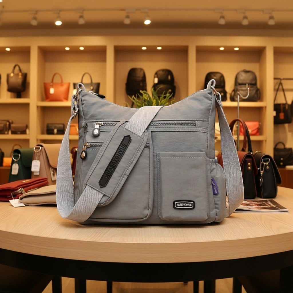 ZenZon Nordic grey nylon crossbody bag with multiple zippered pockets and an adjustable strap in a retail store.