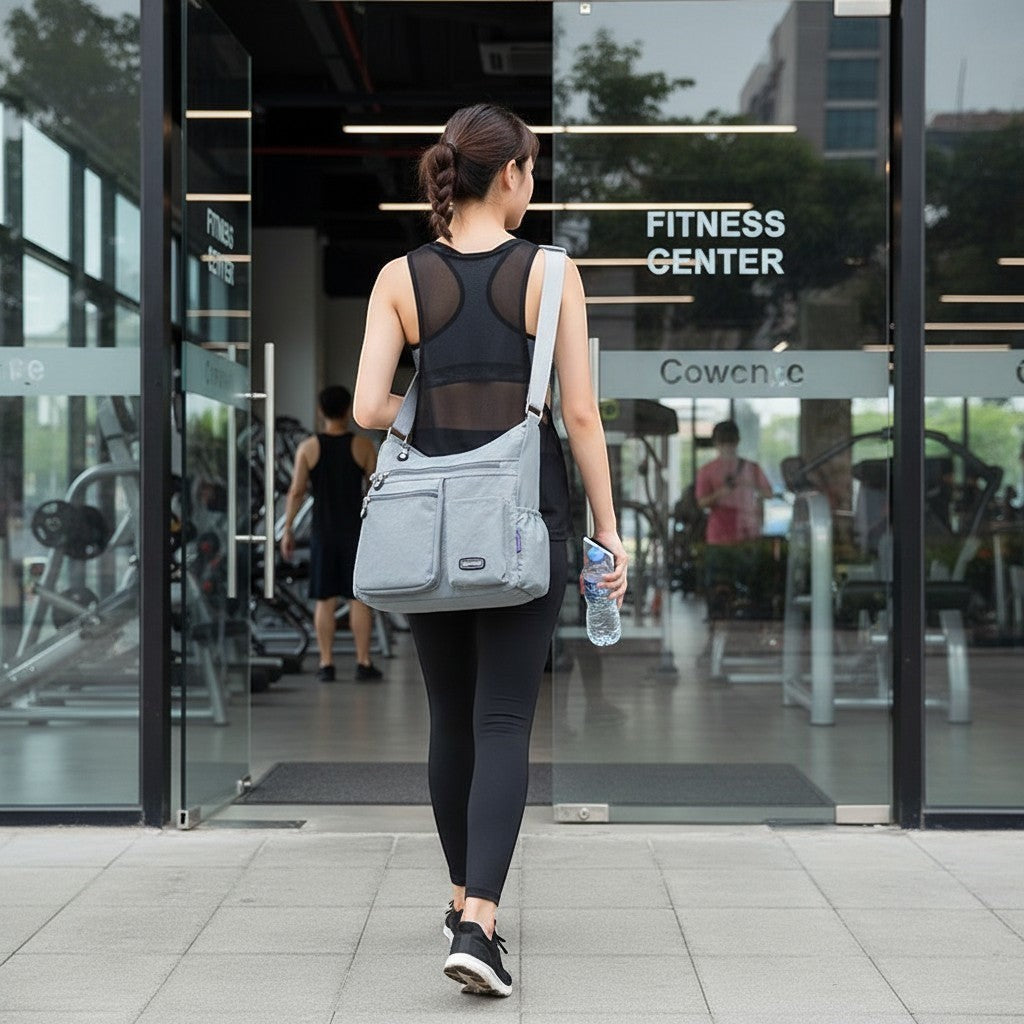 ZenZon Nordic grey nylon crossbody bag with multiple pockets worn by a woman walking into a fitness center